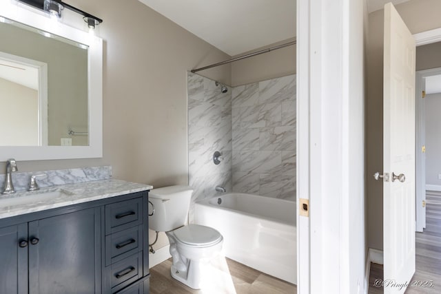 full bathroom featuring hardwood / wood-style flooring, tiled shower / bath, vanity, and toilet