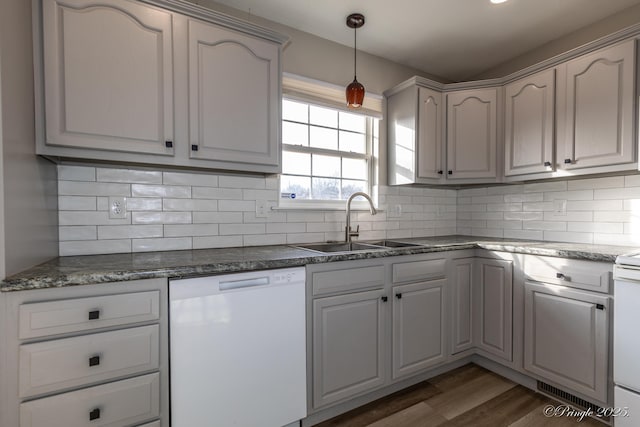 kitchen with sink, dark hardwood / wood-style flooring, dishwasher, pendant lighting, and backsplash