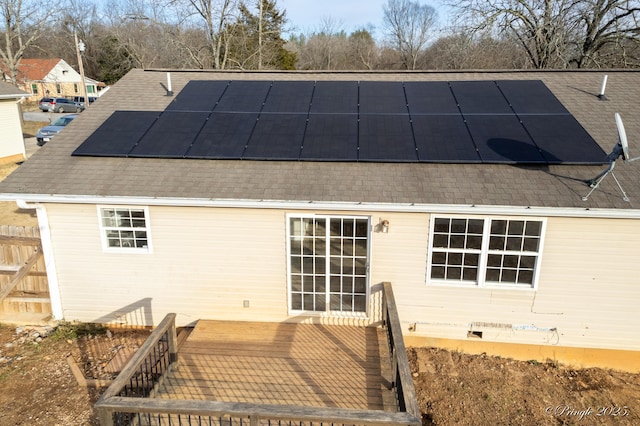 rear view of house with a wooden deck and solar panels