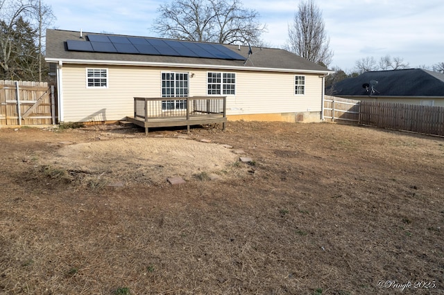 rear view of house featuring a wooden deck and solar panels