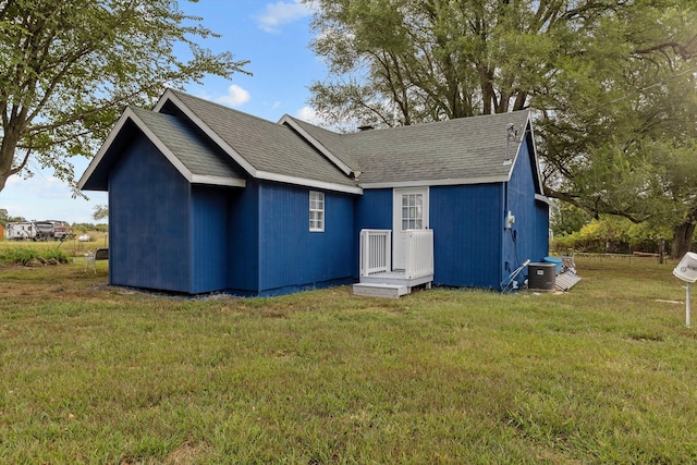 rear view of property featuring central AC unit and a lawn