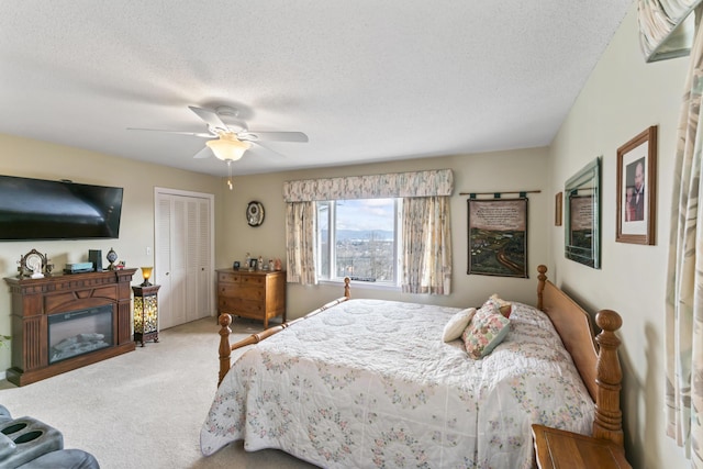 bedroom with ceiling fan, carpet, a textured ceiling, and a closet