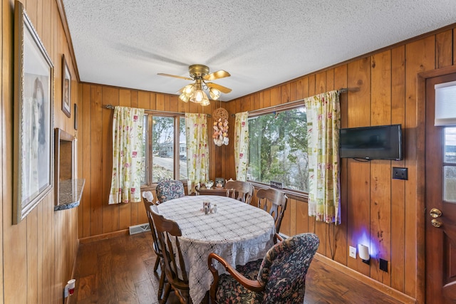 dining area featuring dark wood-type flooring and wood walls