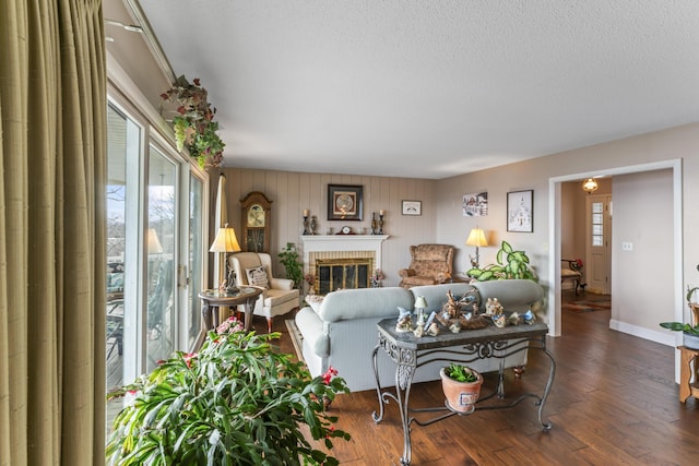 living room with wood-type flooring, a brick fireplace, and a textured ceiling