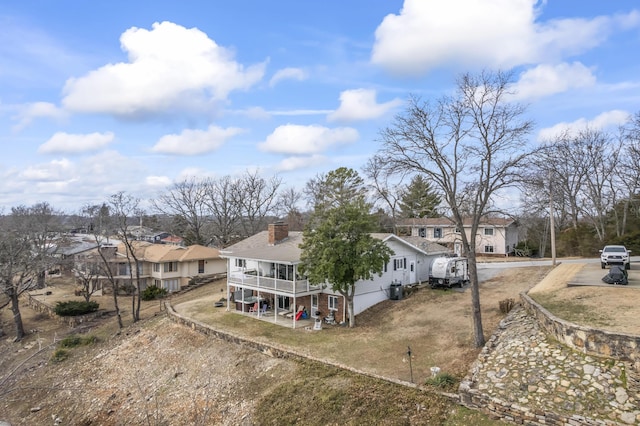 view of front of house with a residential view, driveway, a chimney, and a balcony