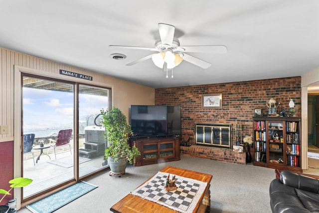 carpeted living room with a brick fireplace, visible vents, and ceiling fan