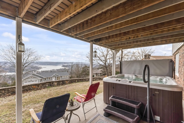 view of patio with a water view and a hot tub