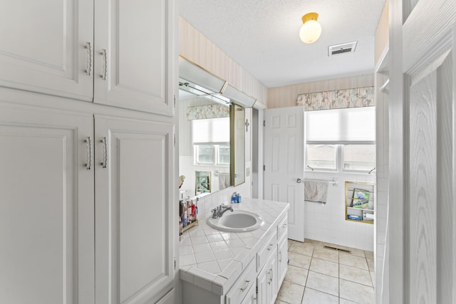 bathroom featuring tile patterned floors, tile walls, a textured ceiling, and vanity