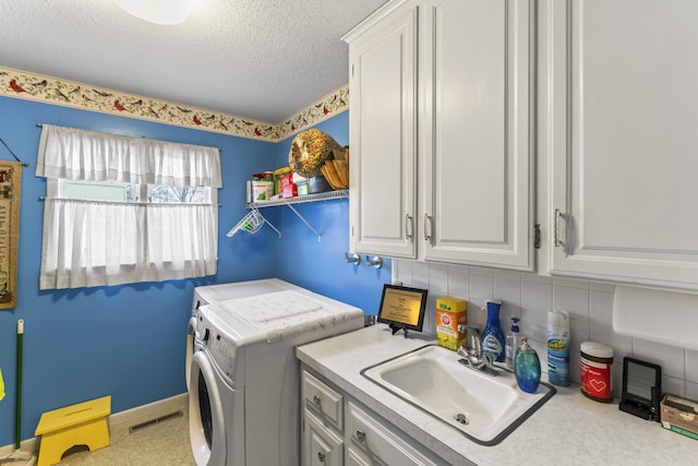 clothes washing area with cabinet space, visible vents, a sink, a textured ceiling, and separate washer and dryer