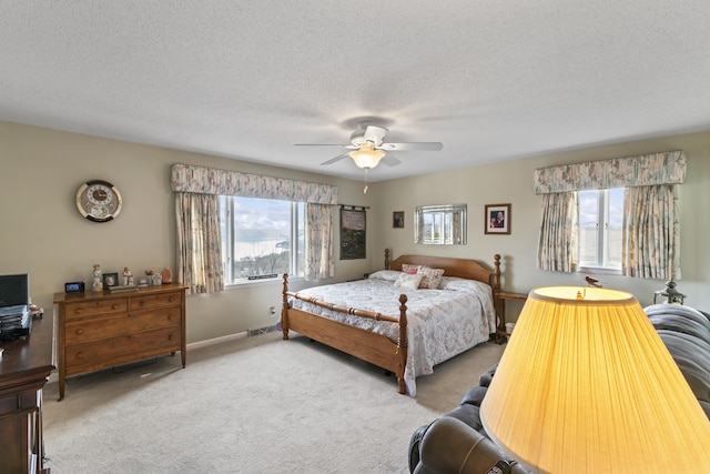 bedroom with multiple windows, a textured ceiling, and light colored carpet