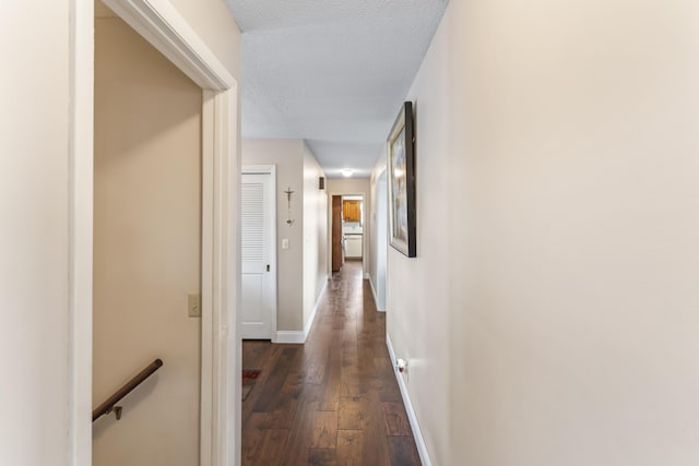 hallway with a textured ceiling and dark hardwood / wood-style flooring