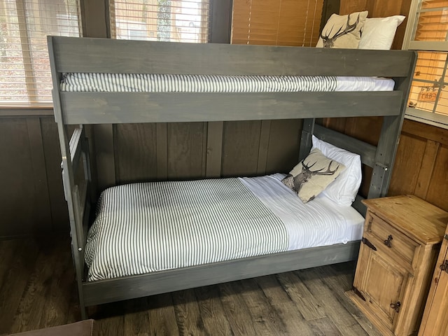 bedroom featuring wooden walls, multiple windows, and wood finished floors