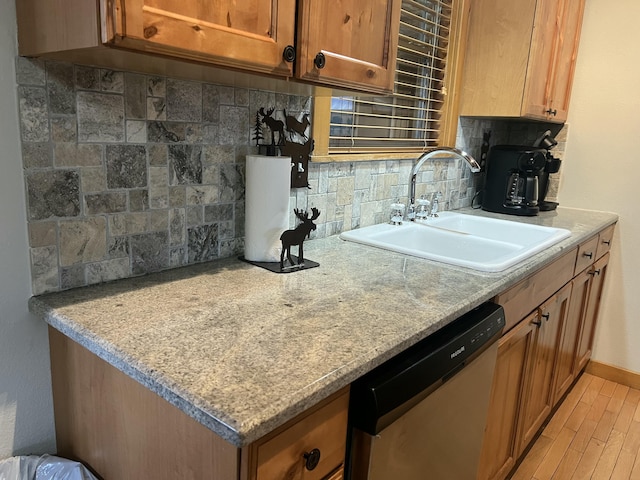 kitchen featuring a sink, stainless steel dishwasher, light wood-type flooring, brown cabinets, and tasteful backsplash