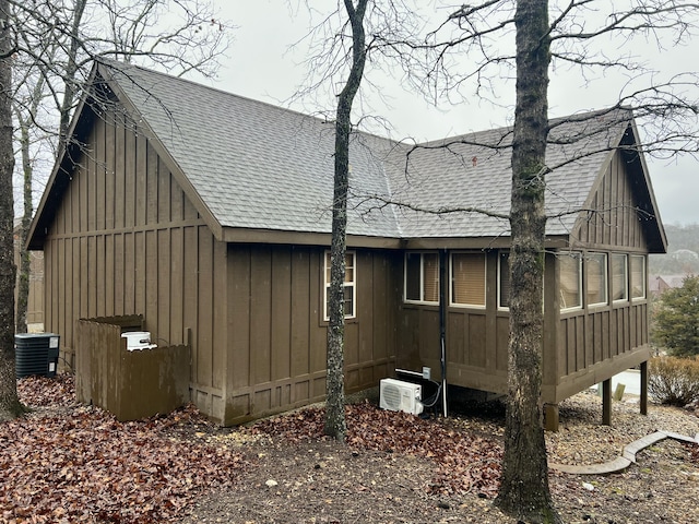 view of property exterior featuring roof with shingles, cooling unit, and board and batten siding