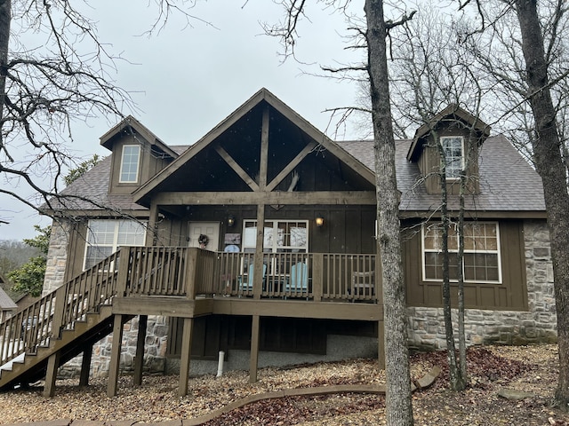 back of property with stone siding, a shingled roof, stairway, and board and batten siding