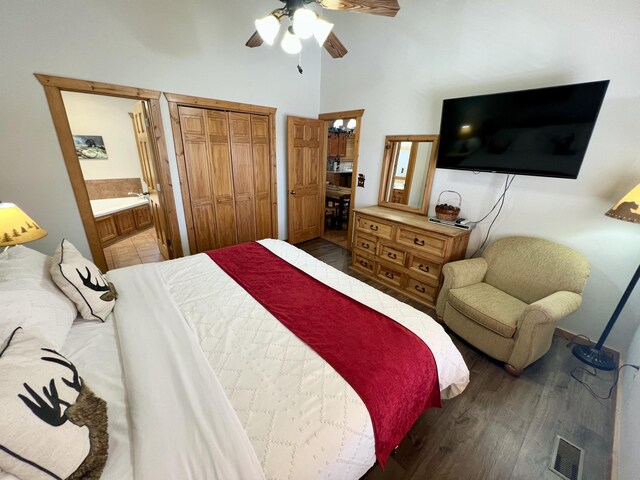 bedroom with visible vents, a towering ceiling, ensuite bath, ceiling fan, and wood finished floors