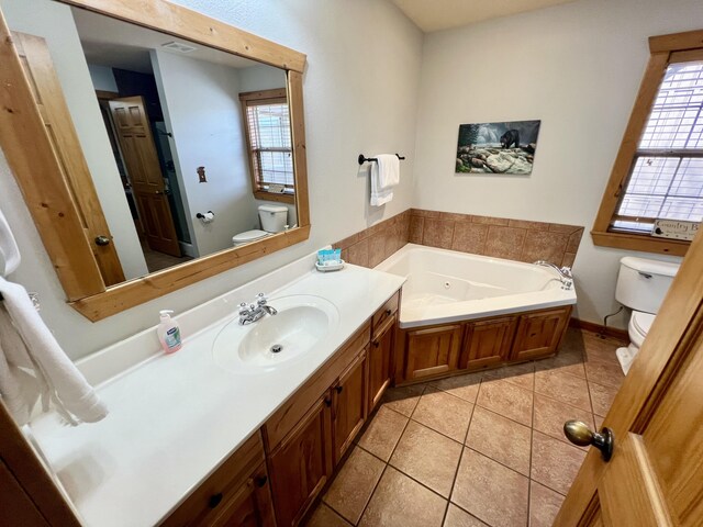 bathroom featuring a garden tub, vanity, toilet, and tile patterned floors