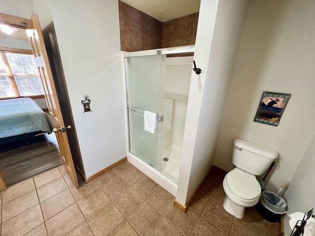 ensuite bathroom with a stall shower, baseboards, toilet, ensuite bath, and tile patterned flooring