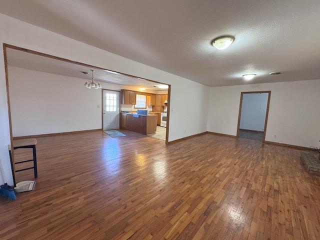 spare room with dark hardwood / wood-style floors, an inviting chandelier, and a textured ceiling