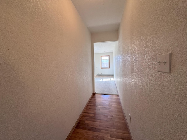 corridor with a baseboard radiator and dark hardwood / wood-style floors