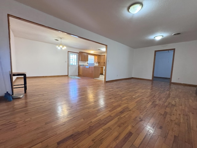 unfurnished living room with dark hardwood / wood-style flooring, a chandelier, and a textured ceiling