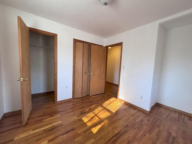 unfurnished bedroom with dark wood-type flooring, multiple closets, and a textured ceiling