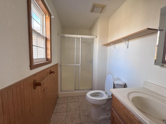 bathroom with tile patterned flooring, wooden walls, vanity, a shower with shower door, and toilet