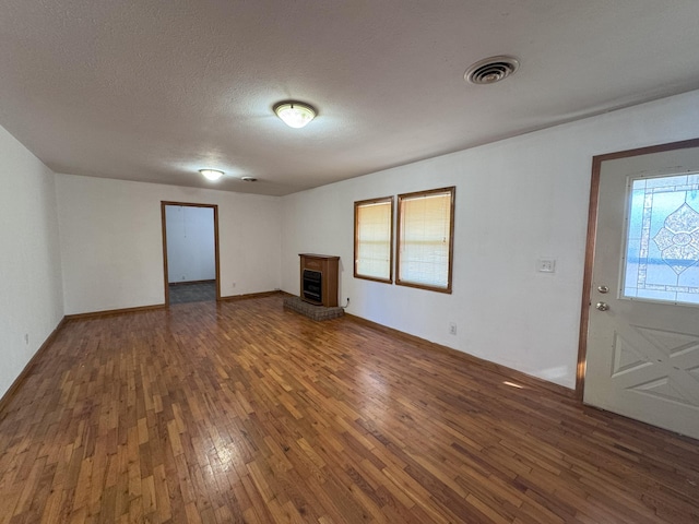 unfurnished living room with dark hardwood / wood-style flooring and a textured ceiling