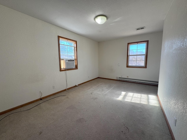 carpeted spare room featuring a healthy amount of sunlight, cooling unit, a textured ceiling, and baseboard heating