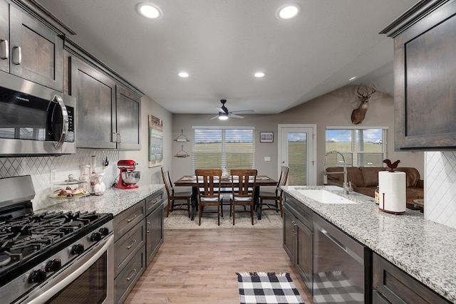 kitchen with sink, dark brown cabinets, stainless steel appliances, and light stone countertops