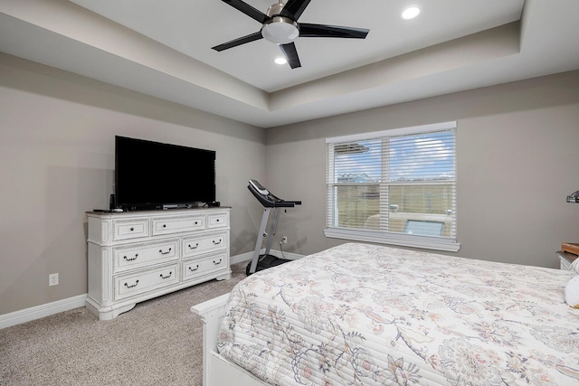 bedroom with light carpet, ceiling fan, and a tray ceiling