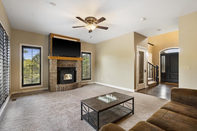 living room with dark carpet, a fireplace, and ceiling fan