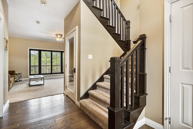 stairway with ceiling fan and wood-type flooring