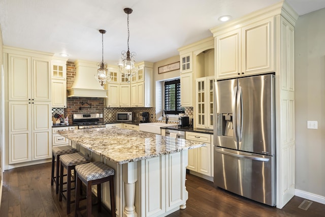 kitchen with sink, stainless steel appliances, a center island, custom exhaust hood, and cream cabinetry