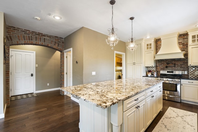 kitchen with a kitchen island, washer / dryer, custom range hood, and stainless steel range with gas stovetop