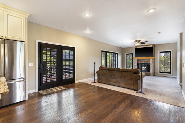 living room with dark wood-type flooring, ceiling fan, and a tile fireplace