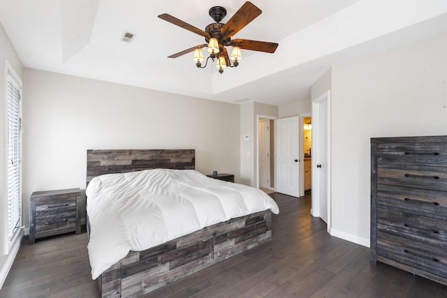 bedroom featuring dark wood-type flooring, ceiling fan, and a tray ceiling