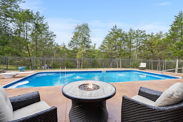 view of swimming pool with a patio, a diving board, pool water feature, and a fire pit