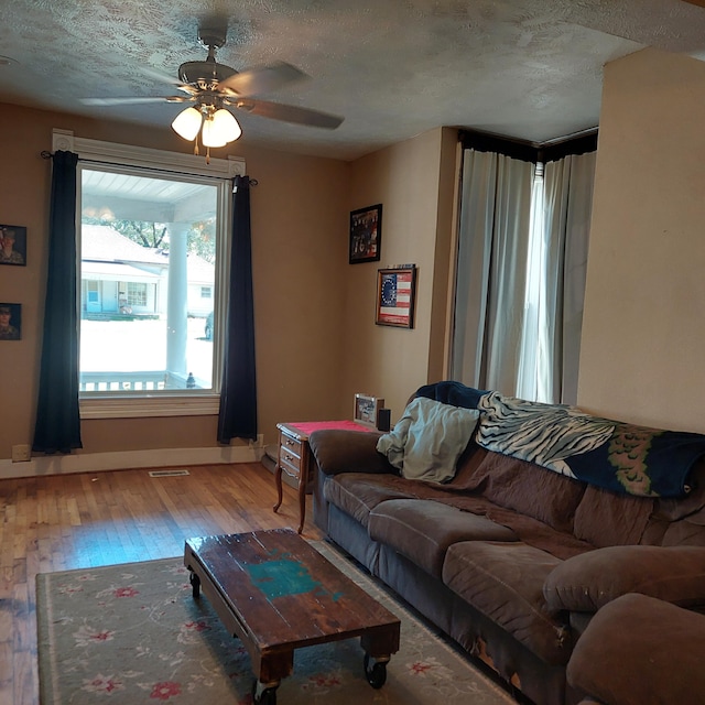 living room featuring ceiling fan, hardwood / wood-style flooring, and a textured ceiling