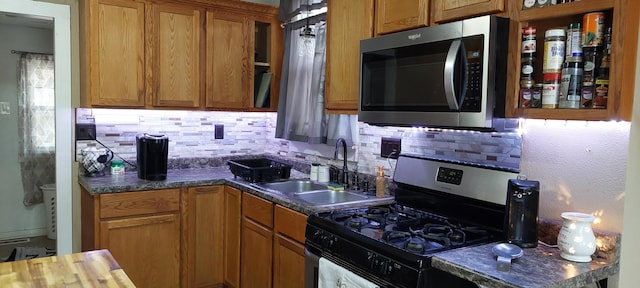 kitchen featuring tasteful backsplash, sink, stainless steel appliances, and dark stone counters