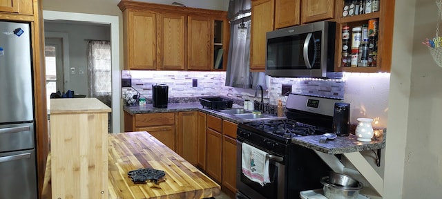 kitchen with appliances with stainless steel finishes, sink, and decorative backsplash