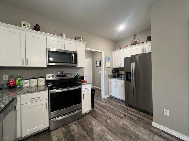 kitchen featuring white cabinetry, dark hardwood / wood-style floors, stainless steel appliances, and dark stone counters