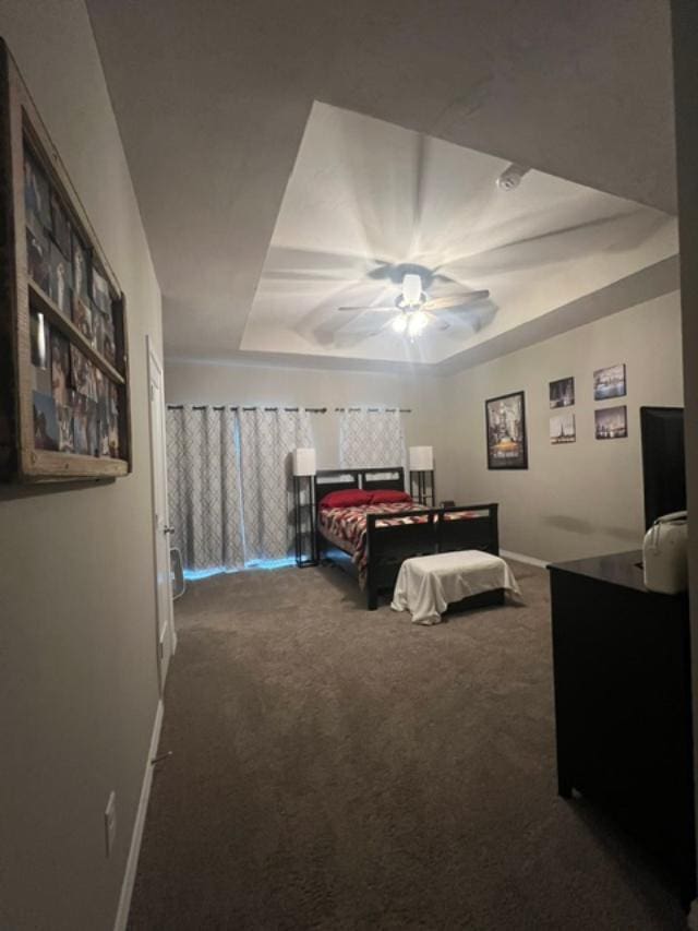 bedroom with ceiling fan, a raised ceiling, and carpet floors