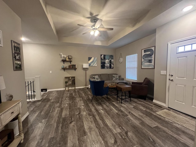 living room featuring ceiling fan, dark hardwood / wood-style flooring, and a raised ceiling