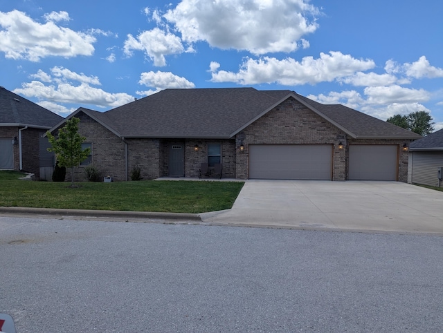 single story home featuring concrete driveway, brick siding, a front lawn, and a garage