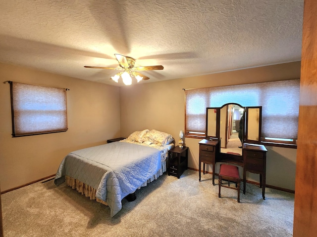 bedroom with ceiling fan, light carpet, and a textured ceiling