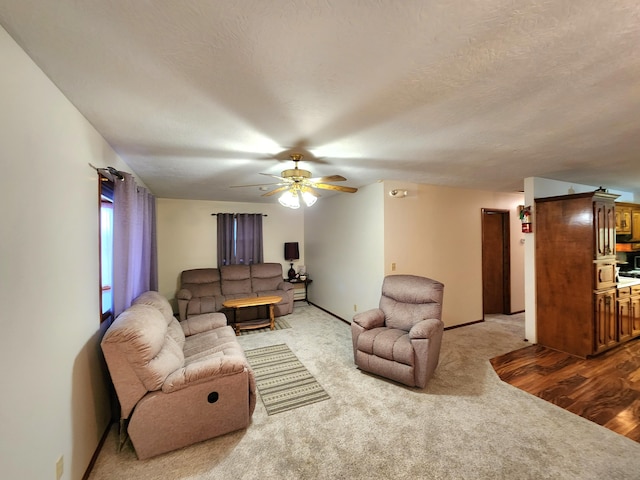 living room with ceiling fan, a textured ceiling, and carpet