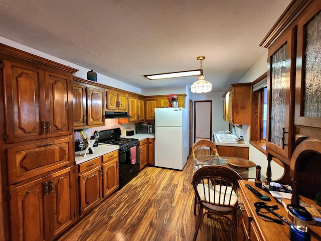 kitchen with hanging light fixtures, hardwood / wood-style floors, gas stove, a textured ceiling, and white fridge