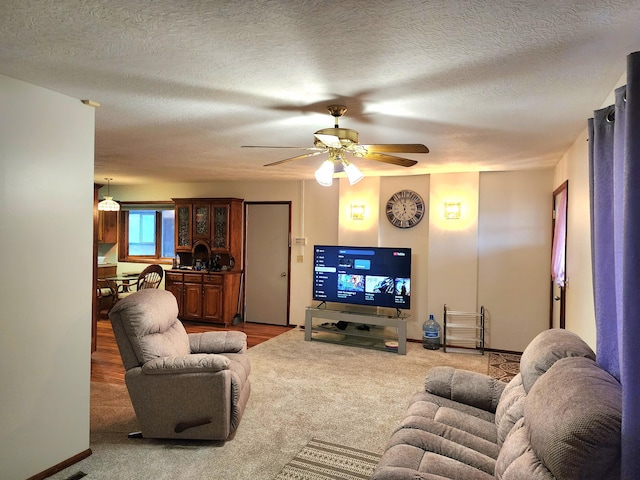 carpeted living room with ceiling fan and a textured ceiling