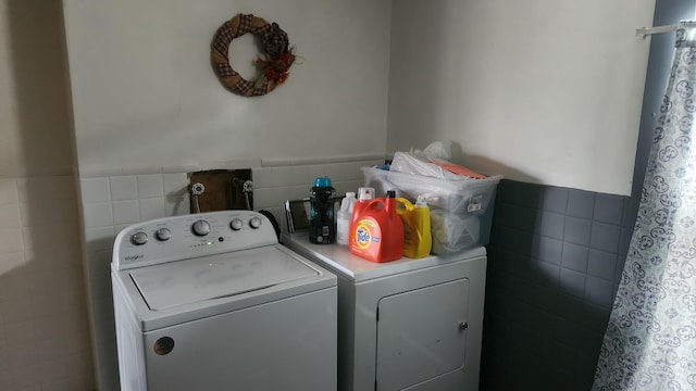 clothes washing area with washing machine and dryer and tile walls